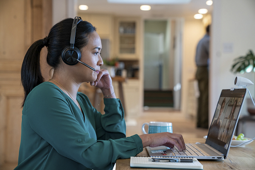 This is a photo of a lady wearing a Poly Voyager Focus 2 headset.