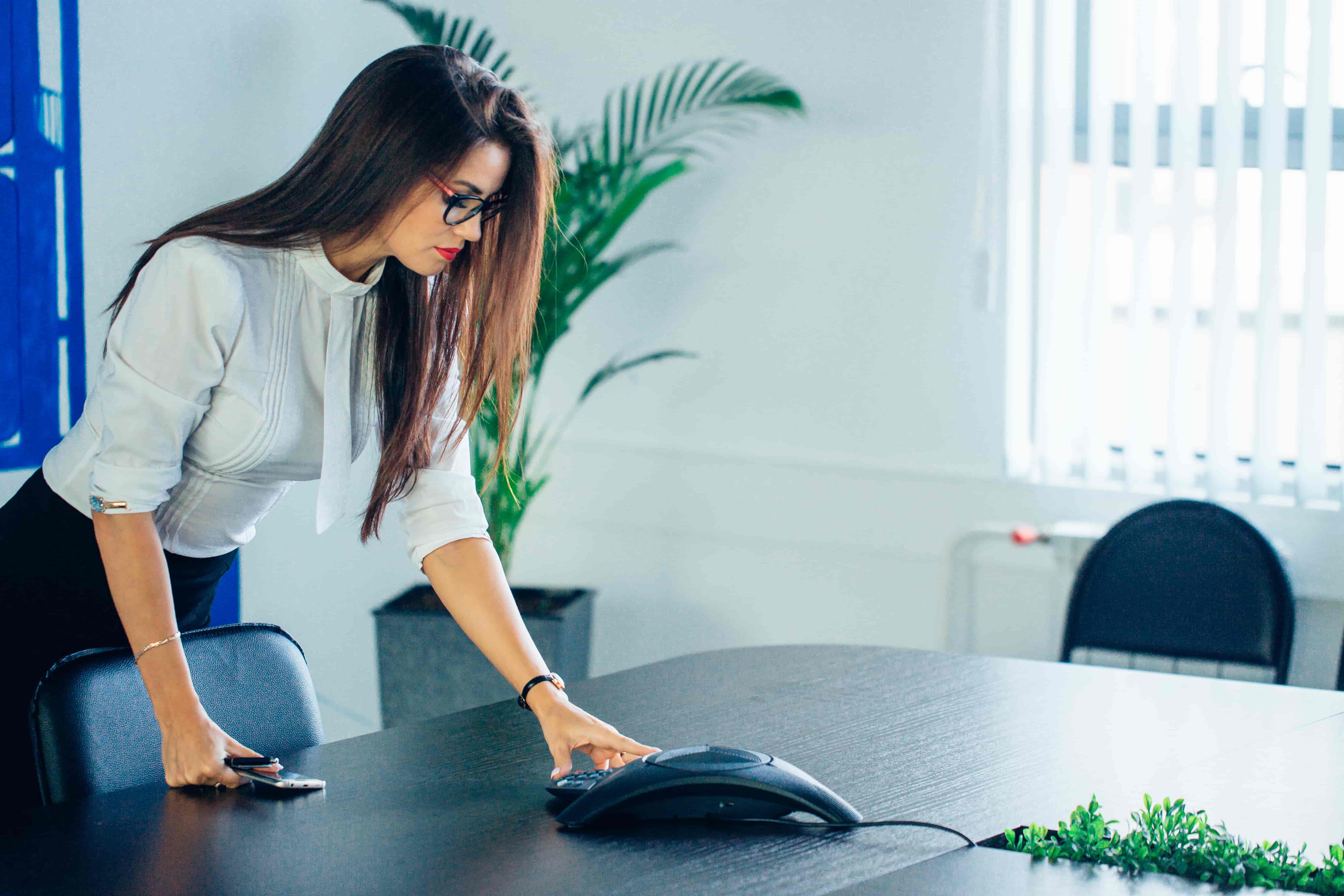 This is a photo of a lady setting up a conference phone.